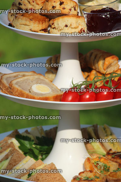Stock image of afternoon tea / cream tea, tiered cake stand, sandwiches, cakes, scones, jam, clotted cream