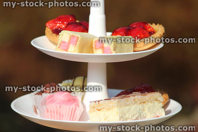 Stock image of afternoon tea / cream tea, tiered cake stand, strawberry tarts, cakes, fondant fancies, Battenberg cakes