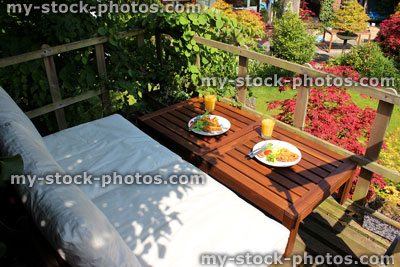 Stock image of outdoors alfresco breakfast, wooden garden furniture, raised treehouse decking