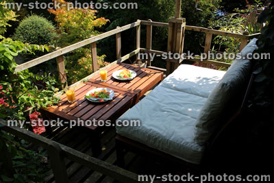 Stock image of outdoors alfresco breakfast, wooden garden furniture, raised treehouse decking