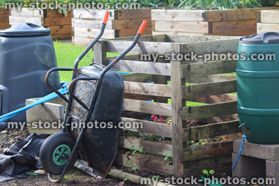 Stock image of wooden compost heap, water butt, plastic compost bin, wheelbarrow, allotment / vegetable garden raised beds