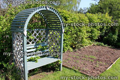 Stock image of allotment vegetable garden with arched wooden seat