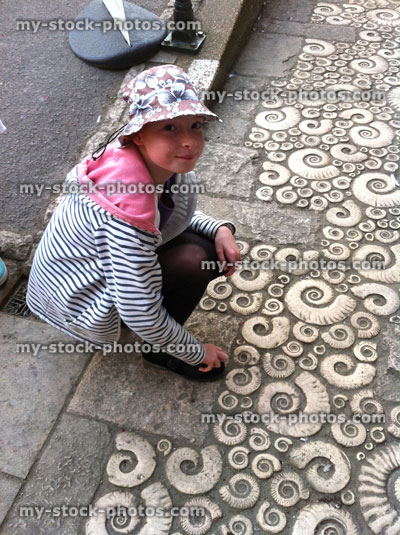 Stock image of young girl viewing ammonite patterned pavement