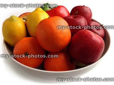 Stock image of white bowl containing artificial plastic and wax fruit