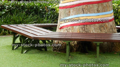 Stock image of London plane tree trunk decorated with ribbons, tree seat, artificial turf