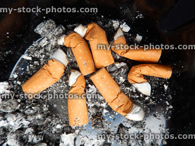 Stock image of cigarette butts / fag ends in dirty ash tray