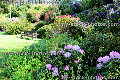 Stock image of wooden bench in rock garden, with flowers