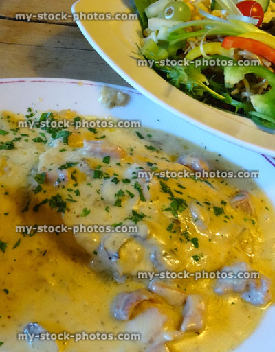 Stock image of baked jacket potato, chicken, cheese sauce, side salad