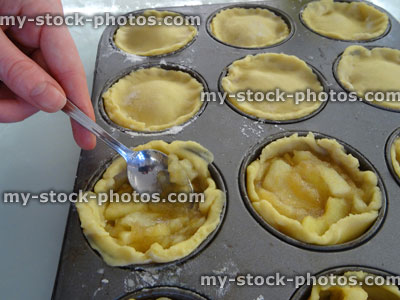 Stock image of home baking, filling individual apple pies / tarts, homemade shortcrust pastry