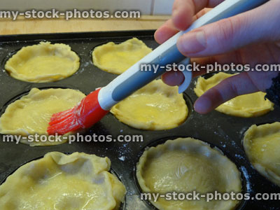 Stock image of glazing / painting egg wash, home baking, homemade pastry, individual apple pies / mince pies