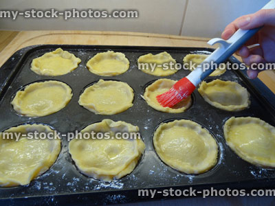 Stock image of glazing / painting egg wash, home baking, homemade pastry, individual apple pies / mince pies