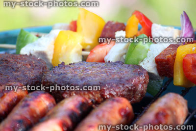 Stock image of kettle charcoal barbecue BBQ in garden, sausages, burgers, kebabs