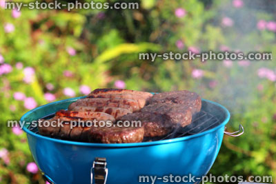Stock image of kettle charcoal barbecue BBQ in garden, sausages, burgers