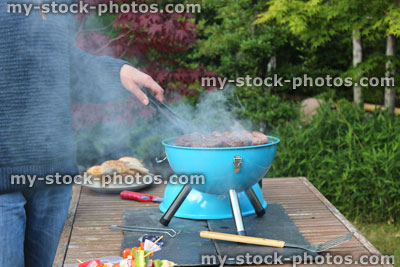 Stock image of man cooking on camping barbecue / portable charcoal BBQ