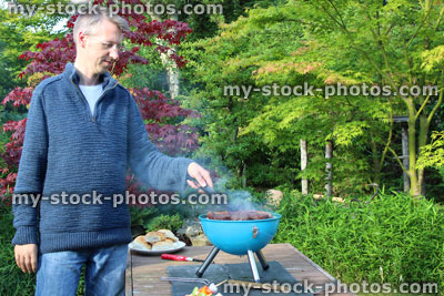 Stock image of man cooking on camping barbecue / portable charcoal BBQ