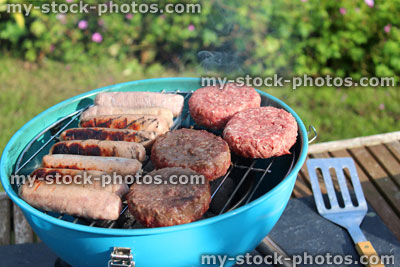 Stock image of kettle charcoal barbecue BBQ in garden, sausages, burgers
