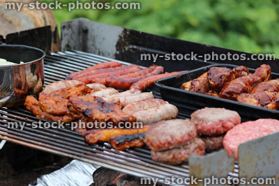 Stock image of charcoal barbecue, garden trolley BBQ grill, sausages, burgers, chicken