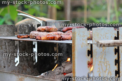Stock image of charcoal barbecue, garden trolley BBQ grill, sausages, burgers, saucepan