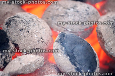 Stock image of smoky, glowing hot charcoal briquettes on barbecue, BBQ hot coals
