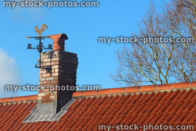 Stock image of new red clay roof tiles, brick chimney, weather vane, new build house