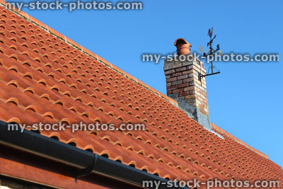 Stock image of new red clay roof tiles, brick chimney, weather vane, new build house