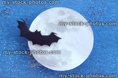 Stock image of black bat silhouette flying in front paper moon, Halloween village / Halloween background