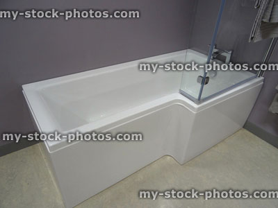 Stock image of modern bathroom, white L shaped shower bath, glass shower screen