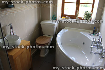 Stock image of modern bathroom suite, with toilet, wash basin and corner bath