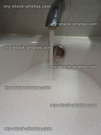 Stock image of modern white bathroom suite / bath, white tiles, pink bubbles bubblebath