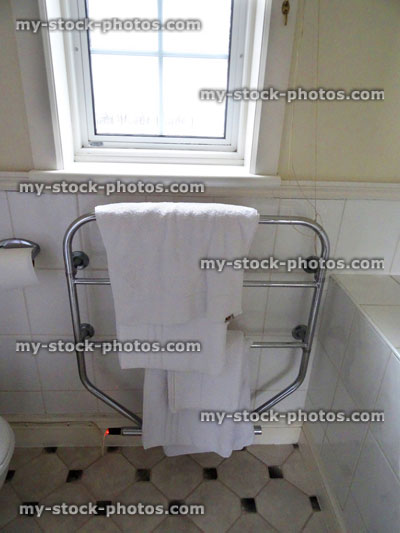 Stock image of bathroom tiles, white towels hanging / chrome towel rail, black white vinyl floor