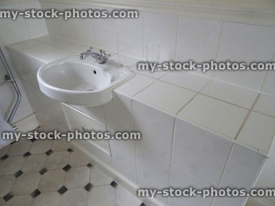 Stock image of white bathroom sink / basin inset in tiled worktop