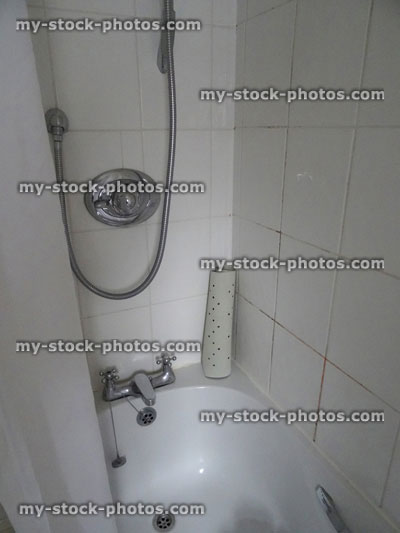 Stock image of bathroom, stainless steel / chrome shower bath, white shower curtain, dirty tiles