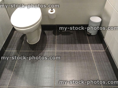 Stock image of modern white bathroom suite, low level integrated WC toilet, grey floor tiles