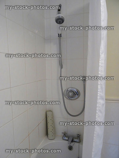 Stock image of bathroom, stainless steel / chrome shower bath, white shower curtain, dirty tiles