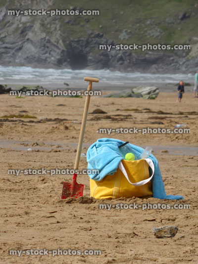 Stock image of beach bag on sand with spade, towel, tennis ball
