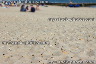 Stock image of sandy beach / seaside in summer, blurred people sunbathing