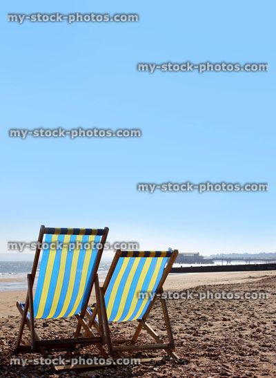 Stock image of blue and yellow striped deckchairs on English beach, poster, banner