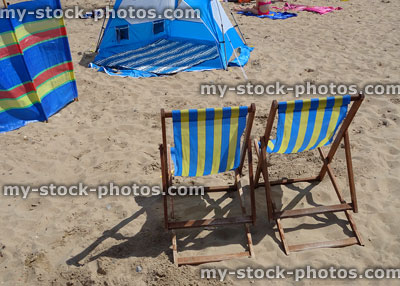 Stock image of sandy seaside beach with wooden deckchairs, windbreak, tent