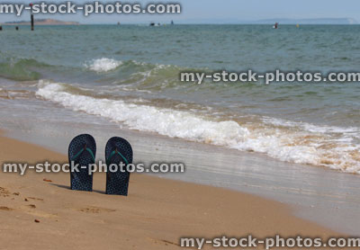 Stock image of flip flops / thongs standing up in sand, beach sandals