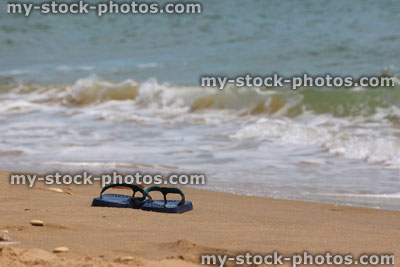 Stock image of flip flops / thongs on sand at seaside, beach sandals