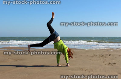 Stock image of young girl doing cartwheels and exercise on beach