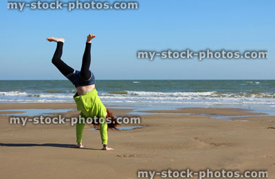 Stock image of child doing cartwheels on beach during seaside holiday