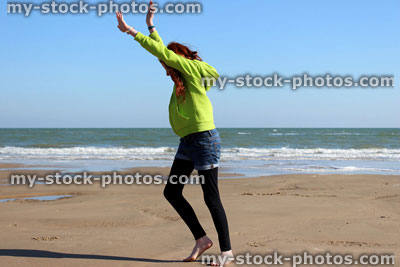 Stock image of girl exercising on beach, about to do cartwheel