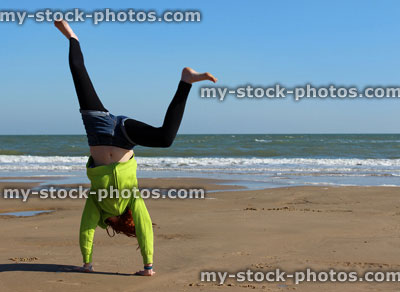 Stock image of child standing on hands doing cartwheel on beach
