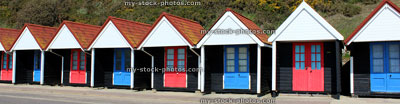 Stock image of banner of colourful English painted beach huts next to cliff