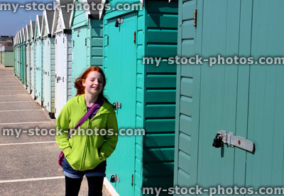 Stock image of girl walking by colourful English painted beach huts