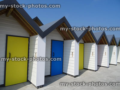 Stock image of white beach huts with yellow and blue doors