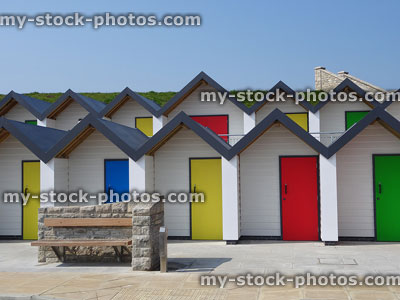 Stock image of concrete beach huts painted white, bright rainbow doors