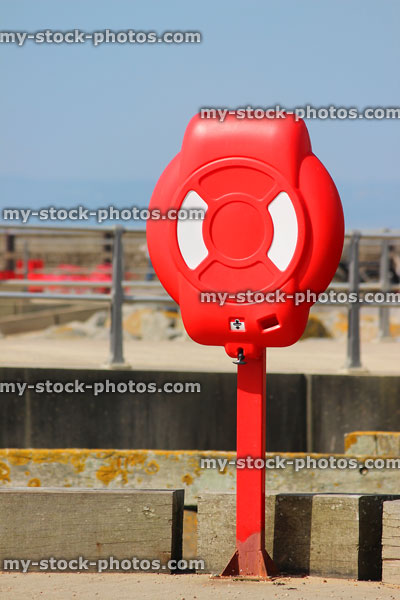 Stock image of lifering / lifebuoy at beach harbour, next to sea