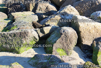 Stock image of natural riprap sea defence on sand, rock armour
